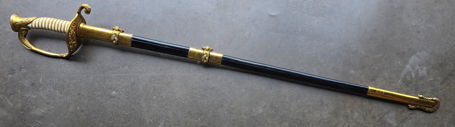 WWI Naval Officer's Sword: Model 1852 USN officer's sword in fine original condition. 100% authentic. 35 ½ inch overall length. Excellent brass hilt with grip retaining its original fish skin wrapping and 100% original w