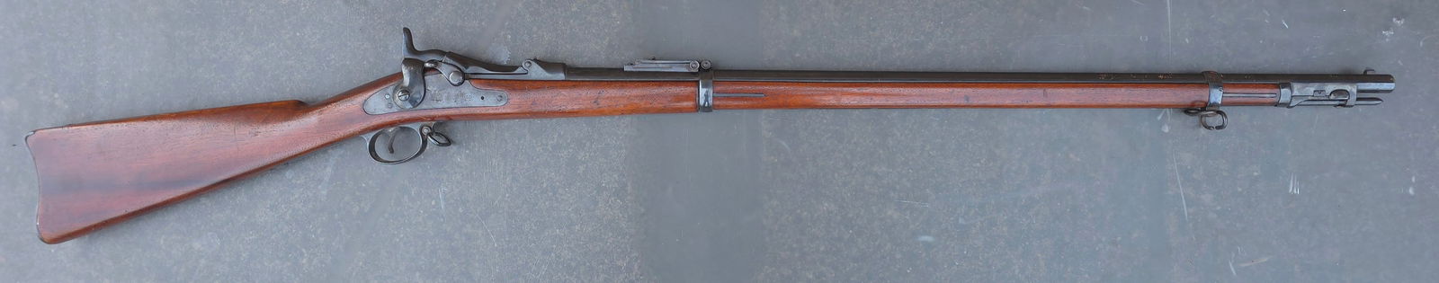 45/70 Trapdoor Springfield Rifle w/ Ramrod Bayonet: A good solid example as refinished. The gun is 100% original and complete and mechanically excellent. All the metal parts have been re-blued and the stock has been varnished. The cartouche is still ni