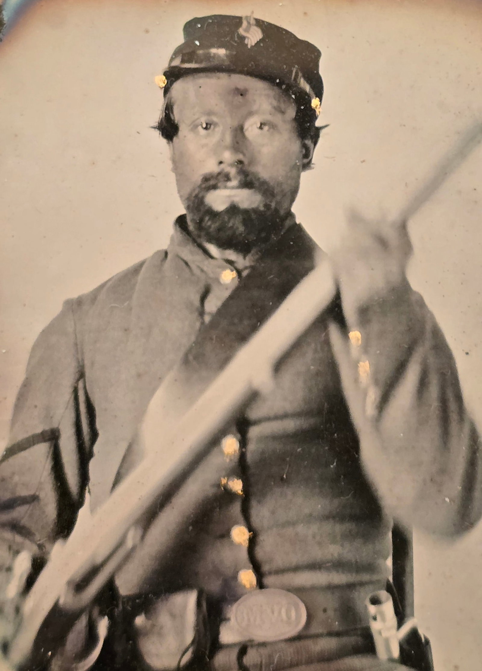 OVM Buckle Ambrotype?: This sixth-plate Civil War ambrotype depicts a seated Union corporal from the Ohio Volunteer Militia (OVM) posing with his percussion rifle-musket held diagonally across his torso. He wears a classic