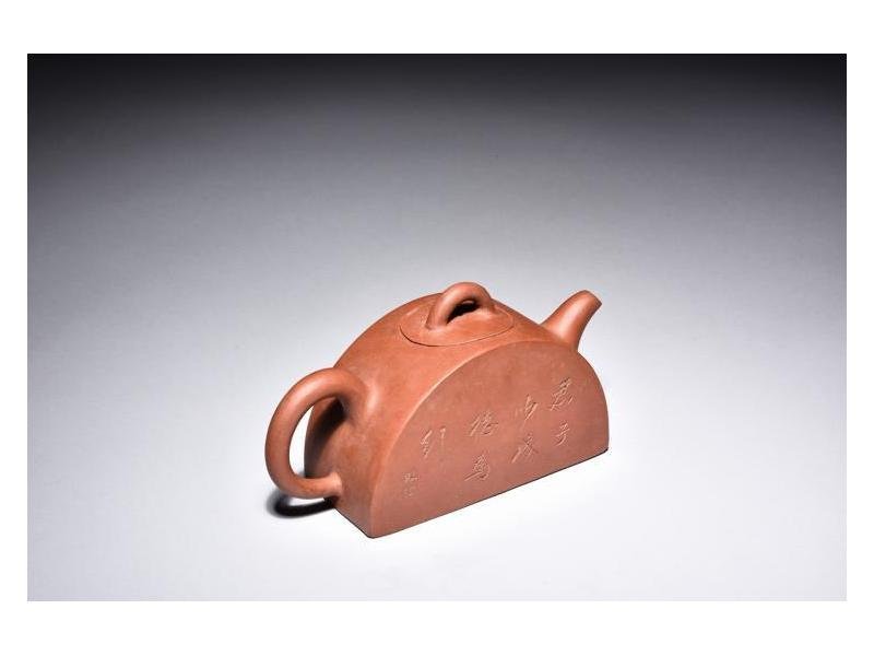 Yixing zisha purple sand Tea Pots & Coffee Pots: The teapot is of half-moon shape, with rounded finial, handle, and spout, with brown clay, colophon on the sides, mark on the bottom.