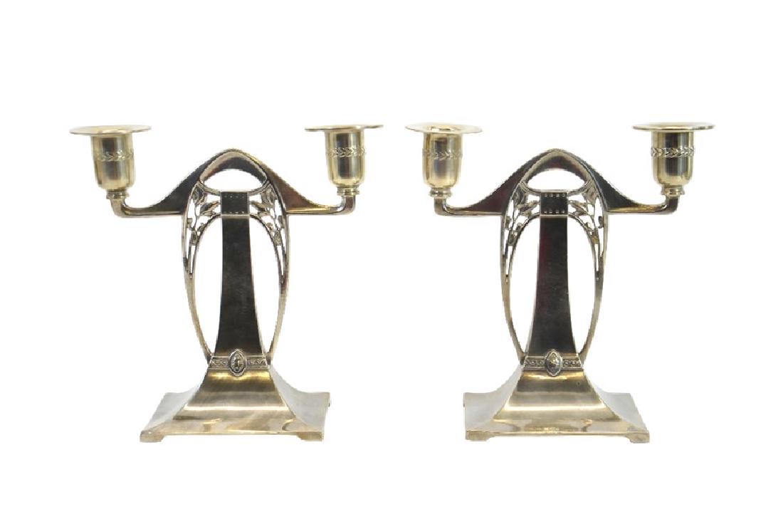WMF, a pair of Jugendstil silver plated twin branch: WMF, a pair of Jugendstil silver plated twin branch candelabra, model 65K, rectangular section trumpet form with open foliate brackets and a yoke sconce support, relief moulded with wreath and scroll