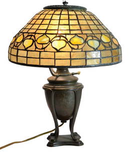 After Tiffany Studios, an Acorn table lamp, leaded: After Tiffany Studios, an Acorn table lamp, leaded amber and opalescent glass shade on a patinated bronze urn base, circa 1920, apparently unmarked, shade 31cm diameter, 38cm high