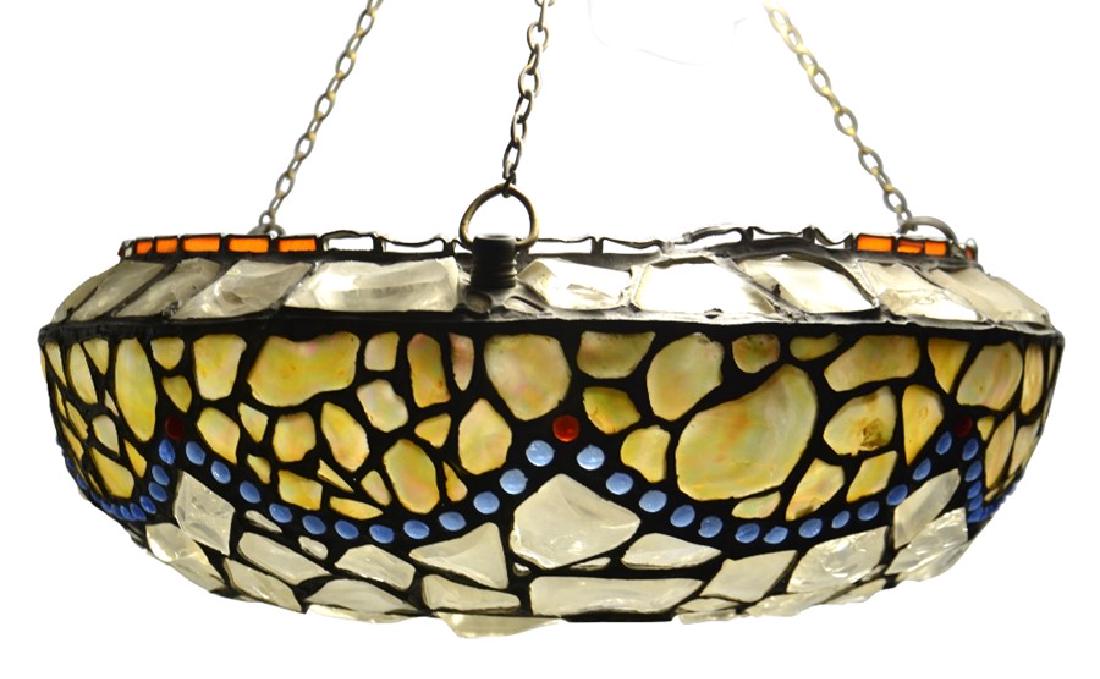 An early 20th century leaded glass and mother of pearl: An early 20th century leaded glass and mother of pearl pendant light shade, circa 1915, swags of shell, beaded with blue cabochons to the edge, above a rock crystal and coloured glass body, suspended 