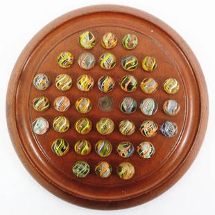 A 37 hole solitaire board on bun feet with 36 German: A 37 hole solitaire board on bun feet with 36 German pontilled swirl marbles, in bright colours 16 to 18 mm, board 23 cm.