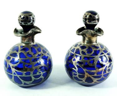 A pair of silver overlay blue glass scent bottles,: A pair of silver overlay blue glass scent bottles, spherical form, foliate scroll banded design with three lipped rims, 17cm high (2)