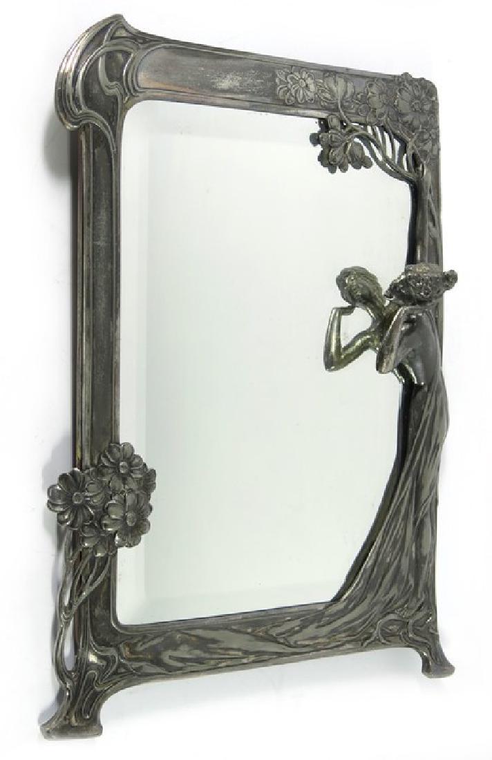 WMF, a Jugendstil silver plated mirror, circa 1906,: WMF, a Jugendstil silver plated mirror, circa 1906, modelled with a semi nude woman and flowering trees, around a bevelled glass, mahogany back, 37cm x 27cm