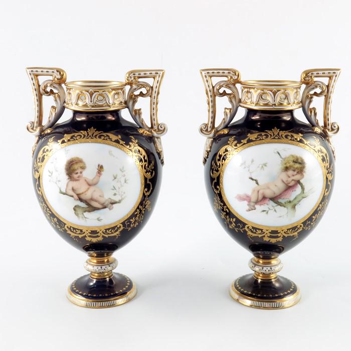Antonin Boullemier for Minton, a pair of painted: Antonin Boullemier for Minton, a pair of painted pedestal vases, twin handled urn form, each with a reclining putto in tree branch, within a tooled gilt foliate scroll cartouche, on blue ground, the h
