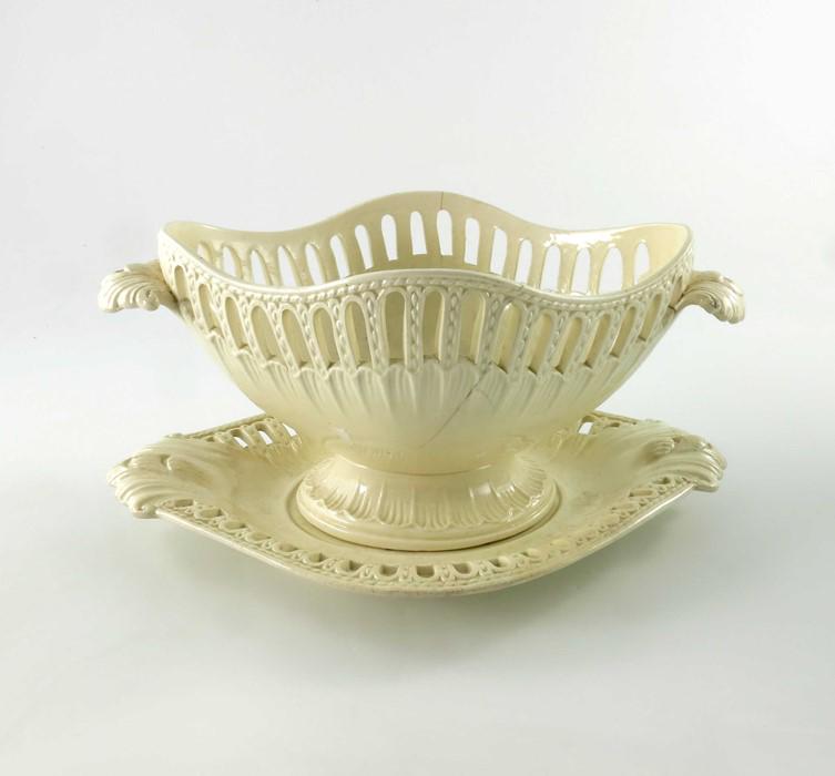 A late 18th Century Creamware pottery oval reticulated: A late 18th Century Creamware pottery oval reticulated basket and stand, twin rope twist handles and foliate moulded terminals, the body with relief moulded masks and foliate swags, 25cm wide (2)