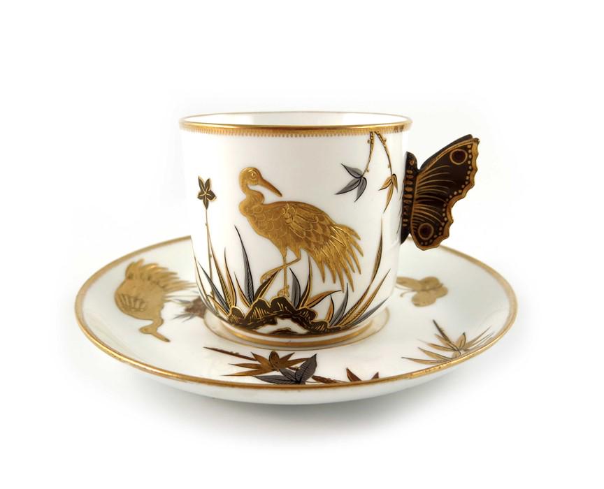 James Hadley for Royal Worcester, an Aesthetic Movement: James Hadley for Royal Worcester, an Aesthetic Movement Japanesque cup and saucer, 1876, relief moulded butterfly handle and tooled gilt and silvered decoration of maple leaves and storks, 14cm diamet