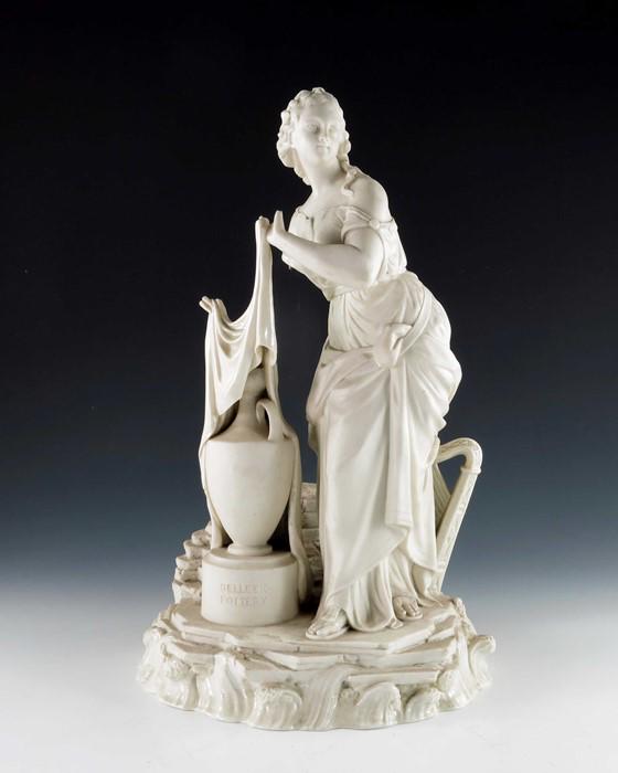 A Belleek first period bisque advertising figure, Erin,: A Belleek first period bisque advertising figure, Erin, modelled as a Classical woman unveiling a vase, with harp beside, impressed to the plinth Belleek Pottery, printed mark, 45.5cm high