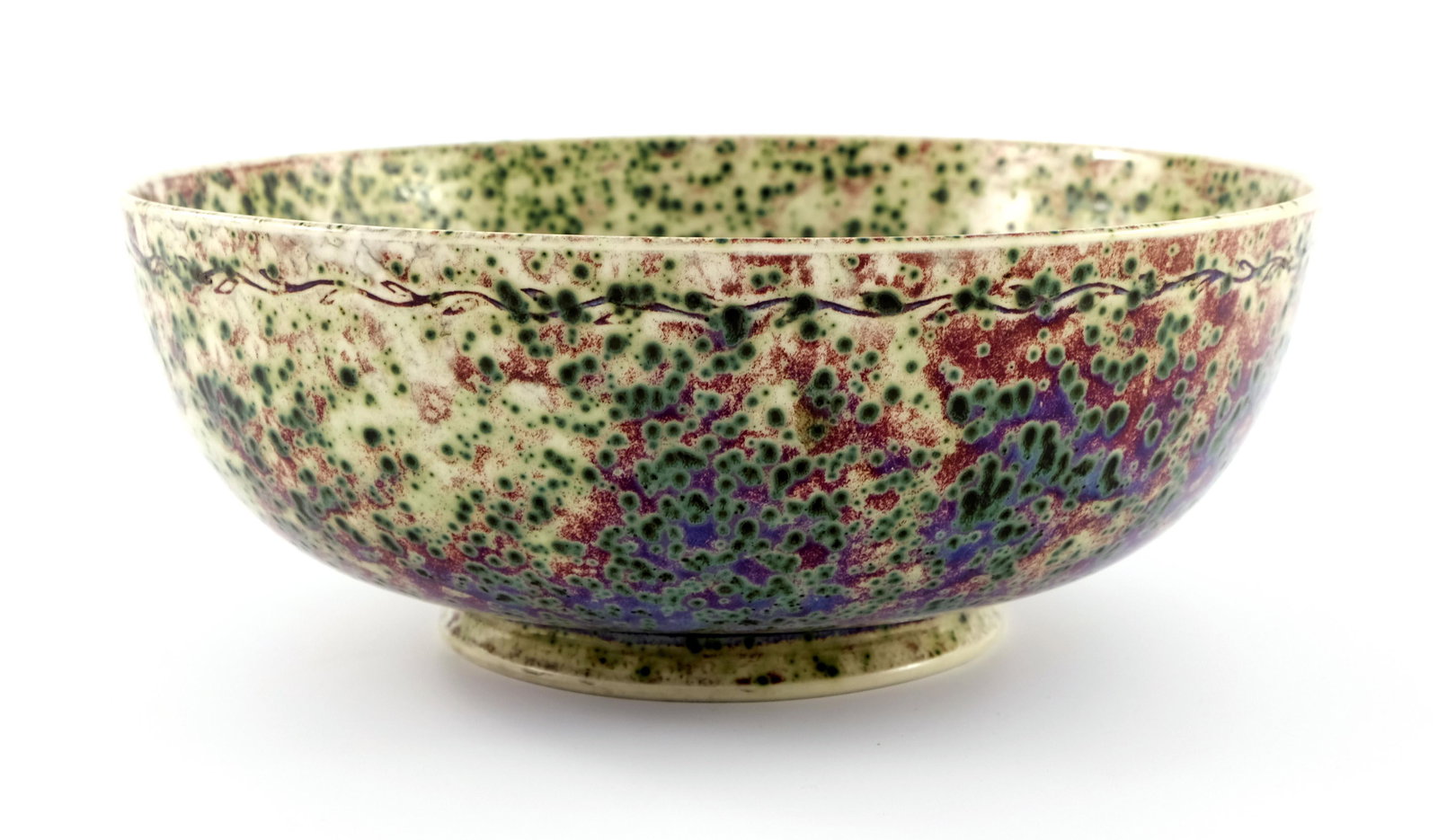 Ruskin Pottery, a High Fired bowl, 1906,: Ruskin Pottery, a High Fired bowl, 1906, footed rounded form, incised with a band of vine decoration, glazed in green speckles over marbles grey, red and purple, impressed marks, 25.5cm diameter