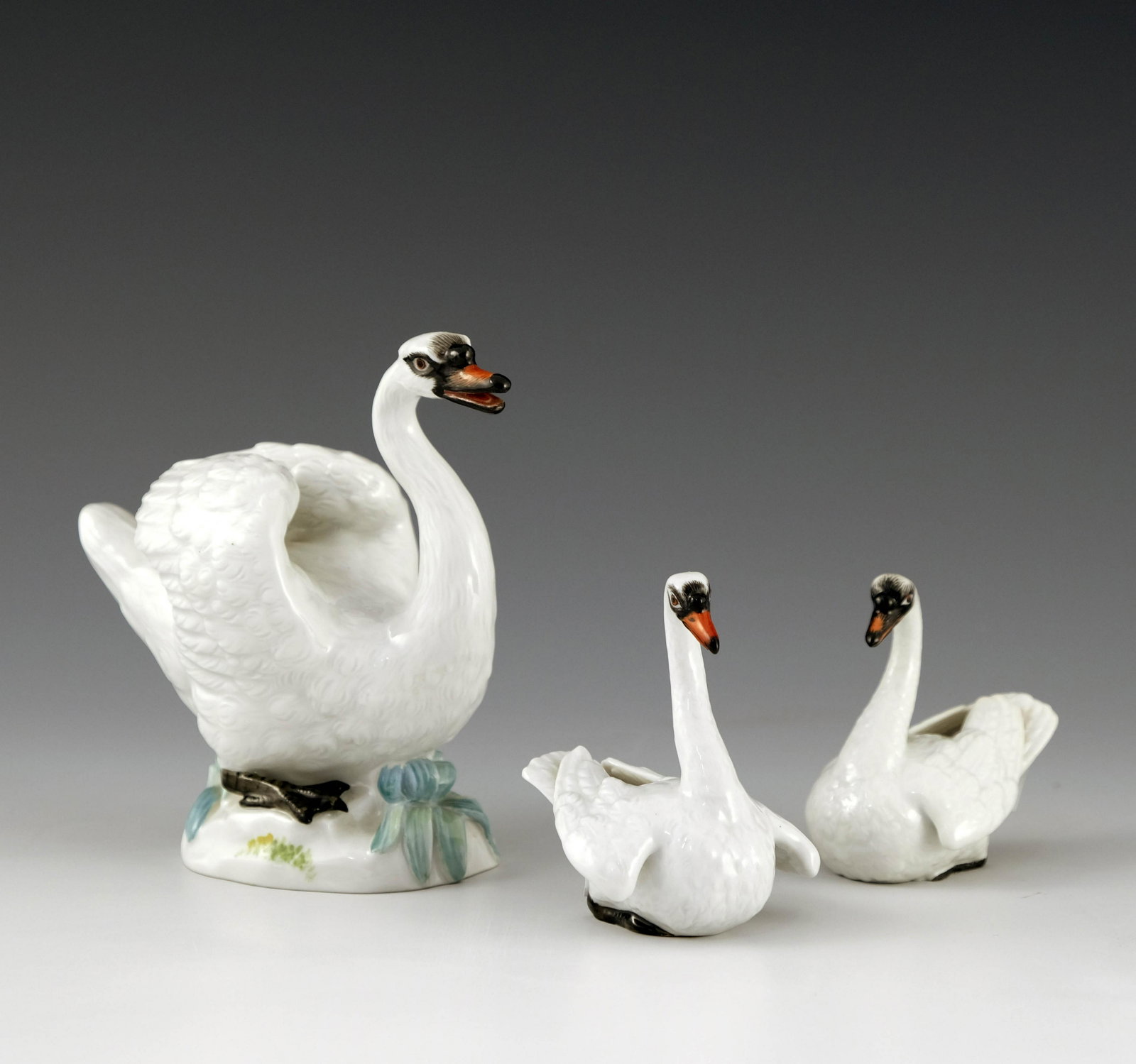 Three Meissen models of swans, 20th Cent: Three Meissen models of swans, 20th Century, all with realistic plumage, the large model on a naturalistic plinth, incised No.214, height 12.5cm, and two smaller, one impressed No.146, the other No.14