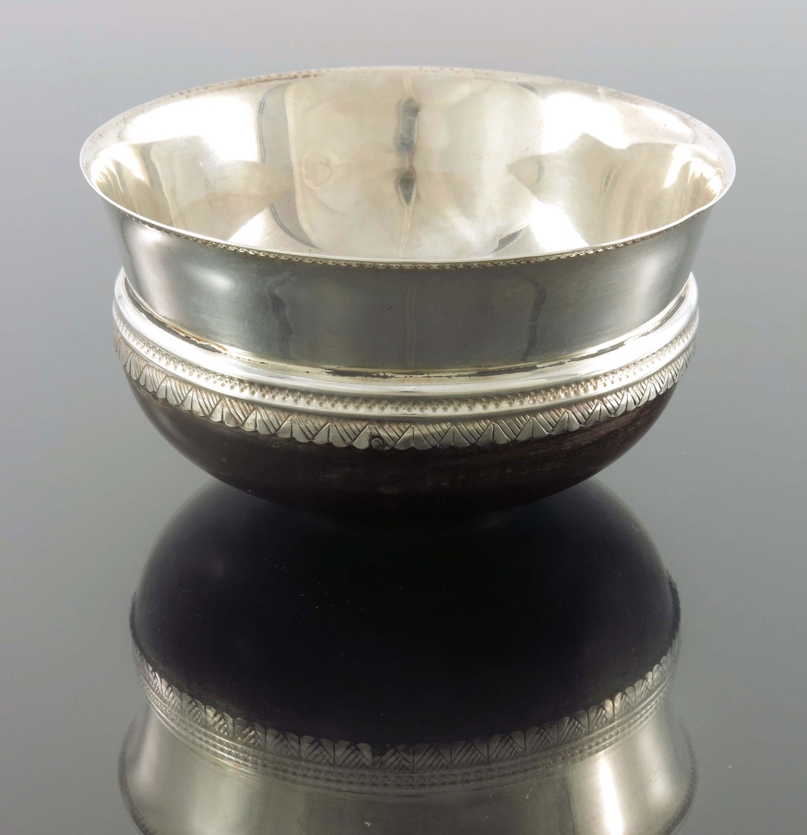 An Arts and Crafts silver and turned woo: An Arts and Crafts silver and turned wood mazer bowl, D and M Davis, Sheffield 1929, squat thistle form decorated with punched floral bands and geometric skirt, 12.5cm diameter