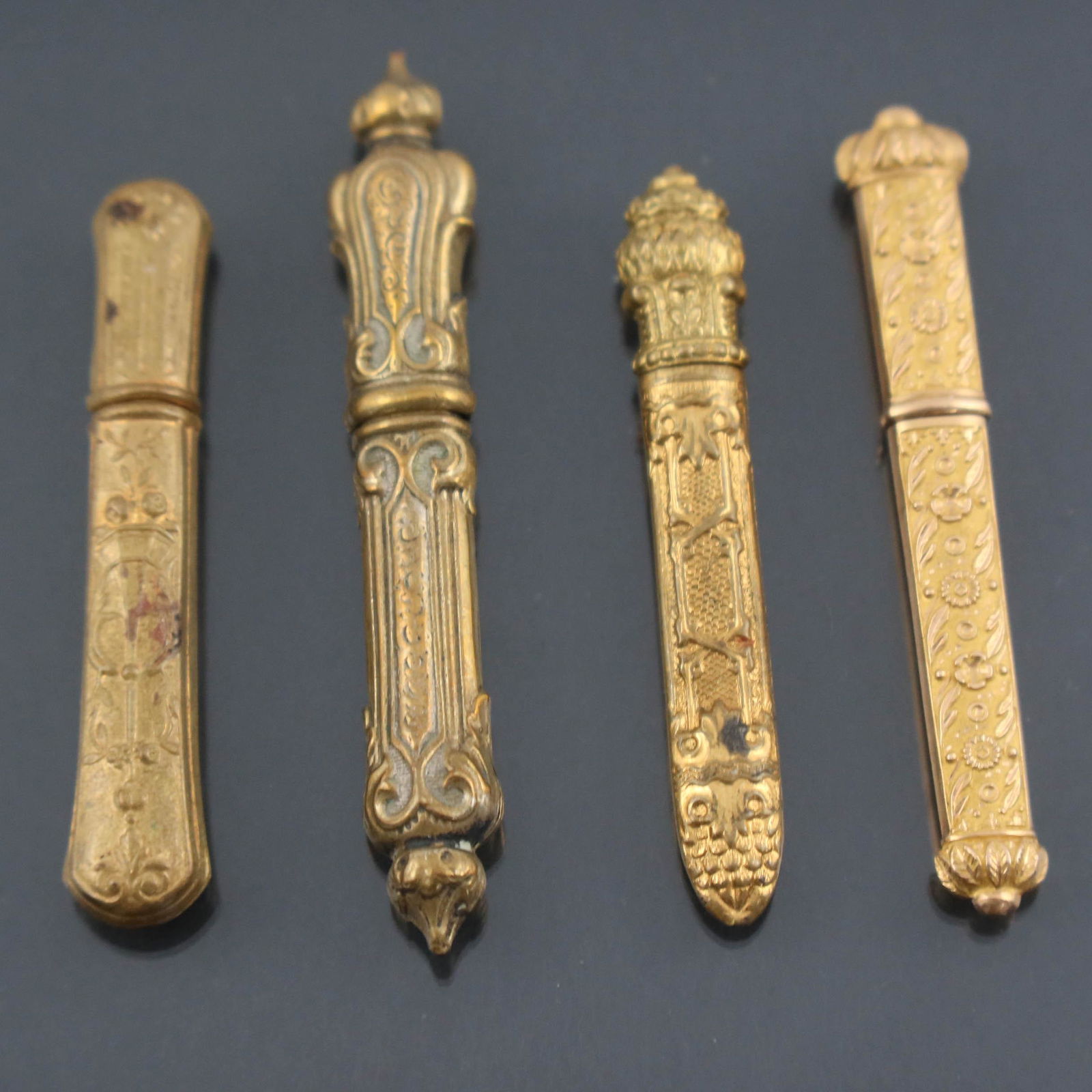 Four yellow metal 19th c needle cases an: Four yellow metal 19th c needle cases, including one French 18ct gold early 19th century, all with various degrees of embossing, from very fine on the bright gold example, to quite low relief on one o