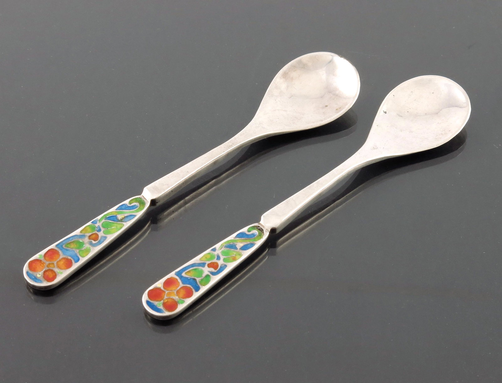 Bernard Instone, a pair of Arts and Craf: Bernard Instone, a pair of Arts and Crafts silver and enamelled coffee spoons, Birmingham 1927, the champleve enamel terminals decorated with stylised knotted flowers, in green, red and blue, planishe