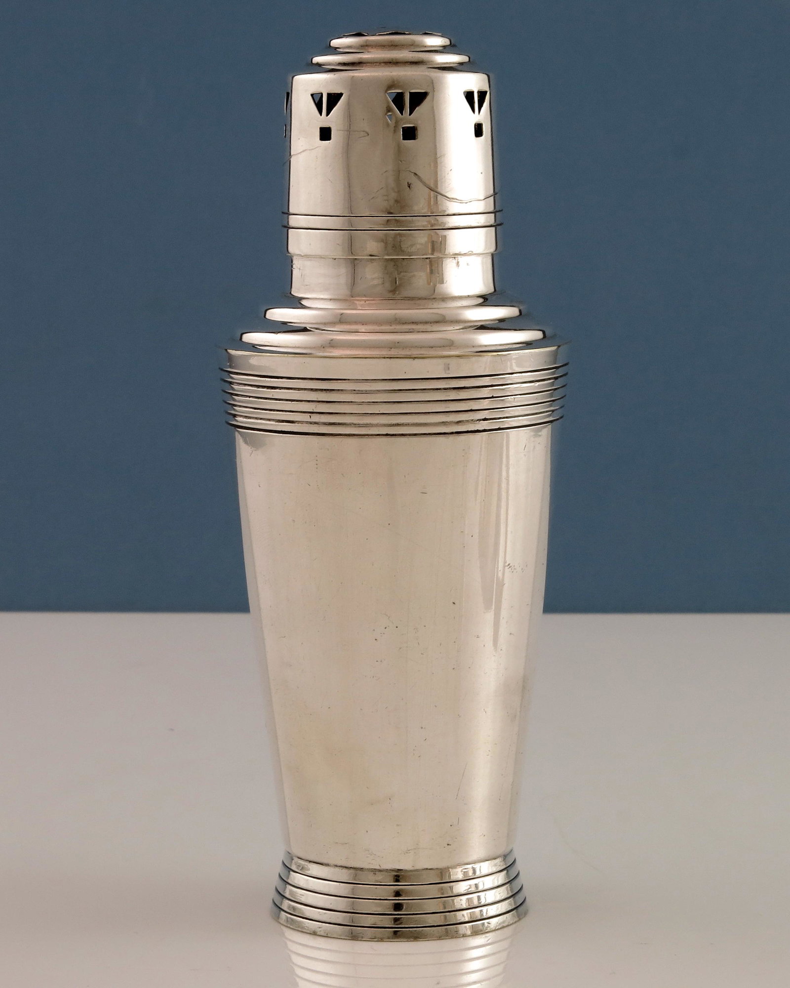 Keith Murray for Mappin and Webb, an Art: Keith Murray for Mappin and Webb, an Art Deco silver plated sugar shaker, circa 1932, conical, stepped shoulder form, pierced to the cap with geometric motifs, incised concentric ring decoration, mode