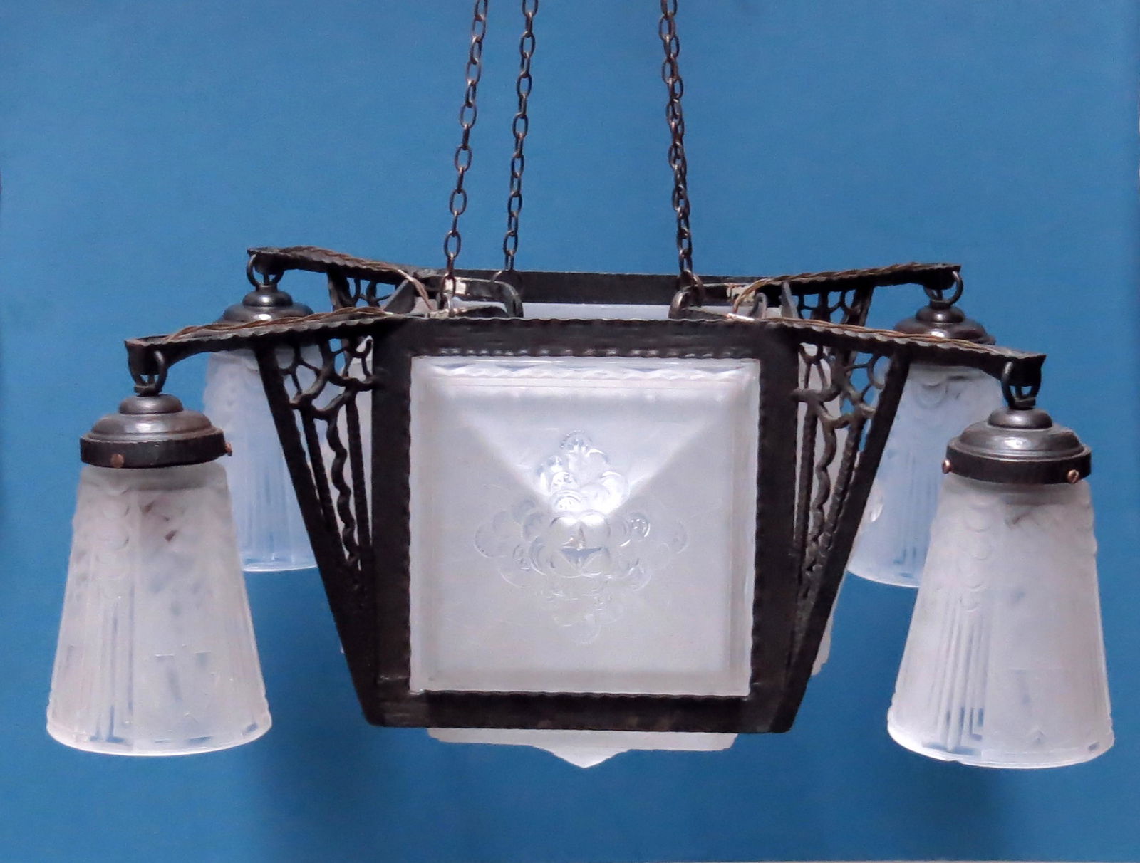 Muller Freres, an Art Deco moulded glass: Muller Freres, an Art Deco moulded glass and wrought iron pendant light, circa 1925, the central cuboid frame with pyramidal floral glass shades, to each side and the underneath, flanked by four brack