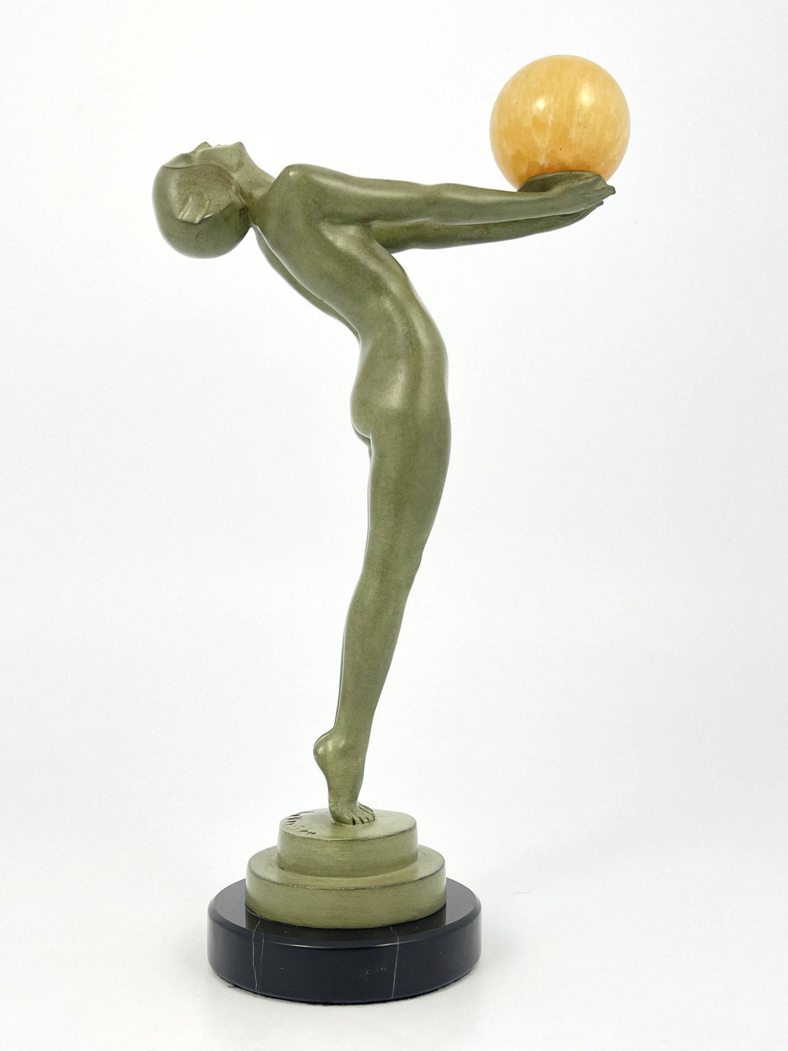 Max Le Verrier, an Art Deco patinated ar: Max Le Verrier, an Art Deco patinated art metal figure, circa 1925, modelled as a nude woman, arms outstretched holding an alabaster sphere, on circular black marble base, signed in cast Le Verrier, s