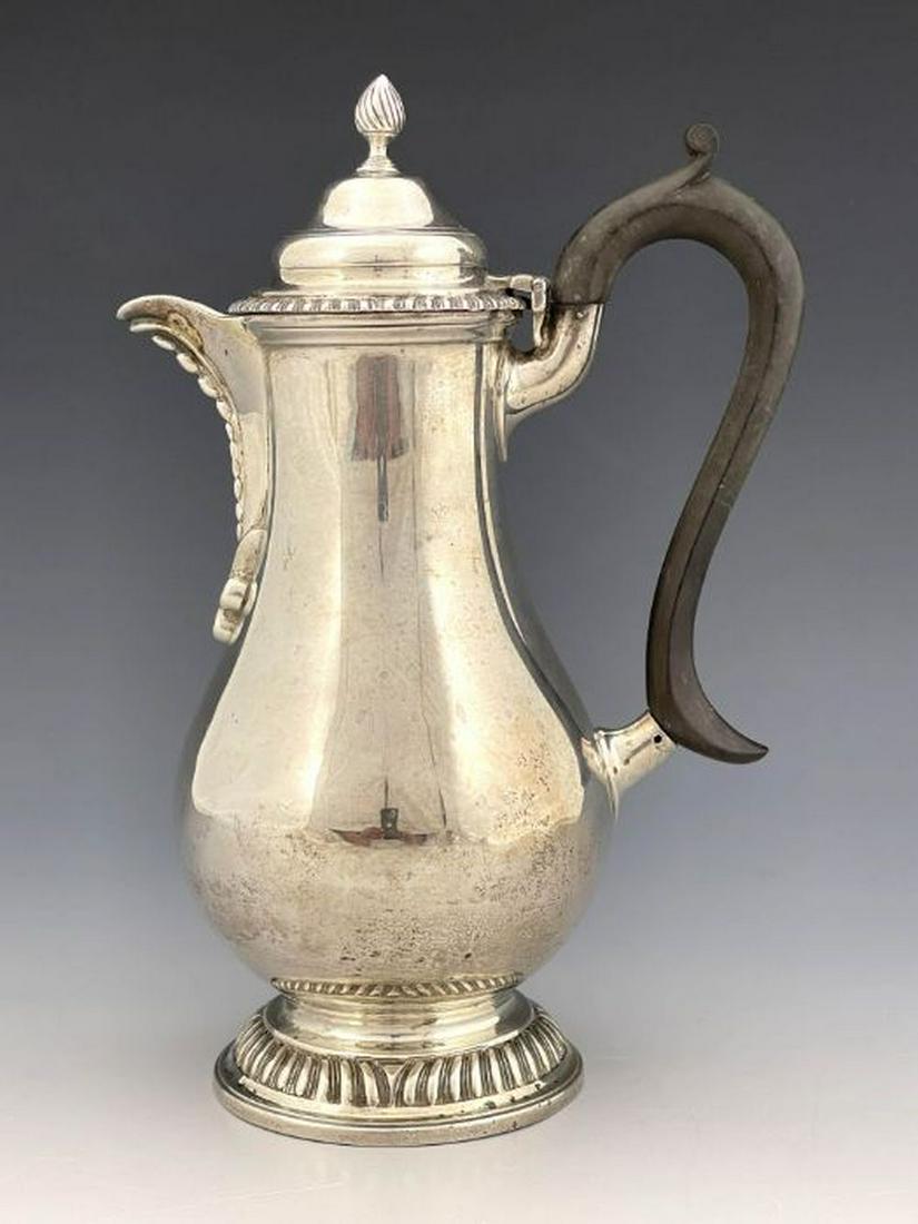 An Edwardian silver hot water jug, Charl: An Edwardian silver hot water jug, Charles Stuart Harris, London 1904, baluster form with gadrooned foot and rim, beaded spout, ogee hinged lid and flame finial, 23cm high, 14.82ozt