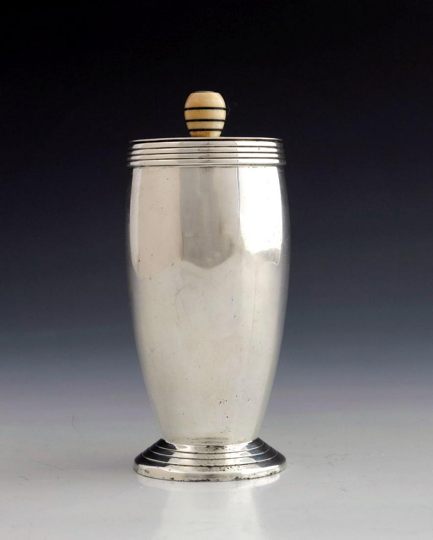 Keith Murray for Mappin and Webb, an Art: Keith Murray for Mappin and Webb, an Art Deco silver sugar caster, London 1934, the barrel form body with concentric reeded rim, on a conical foot with incised banding, the flat lid pierced with geome