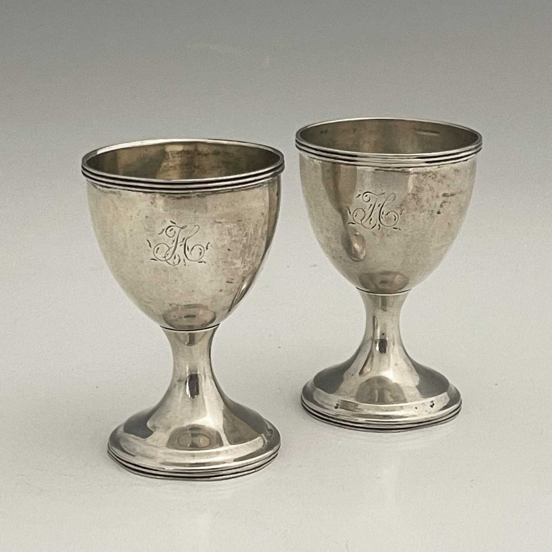 Newcastle. A pair of George III English: Newcastle. A pair of George III English provincial silver egg cups, each of baluster form and decorated with a band of reeding to the rim of both the bowl and foot rim, initialled 'H' in script, sans