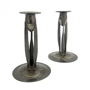 Archibald Knox for Liberty and Co., a pa: Archibald Knox for Liberty and Co., a pair of Tudric Arts and Crafts pewter candlesticks, model 0223, planished and formed of three bladed buttress supports, on domed foliate bases, 23.5cm high