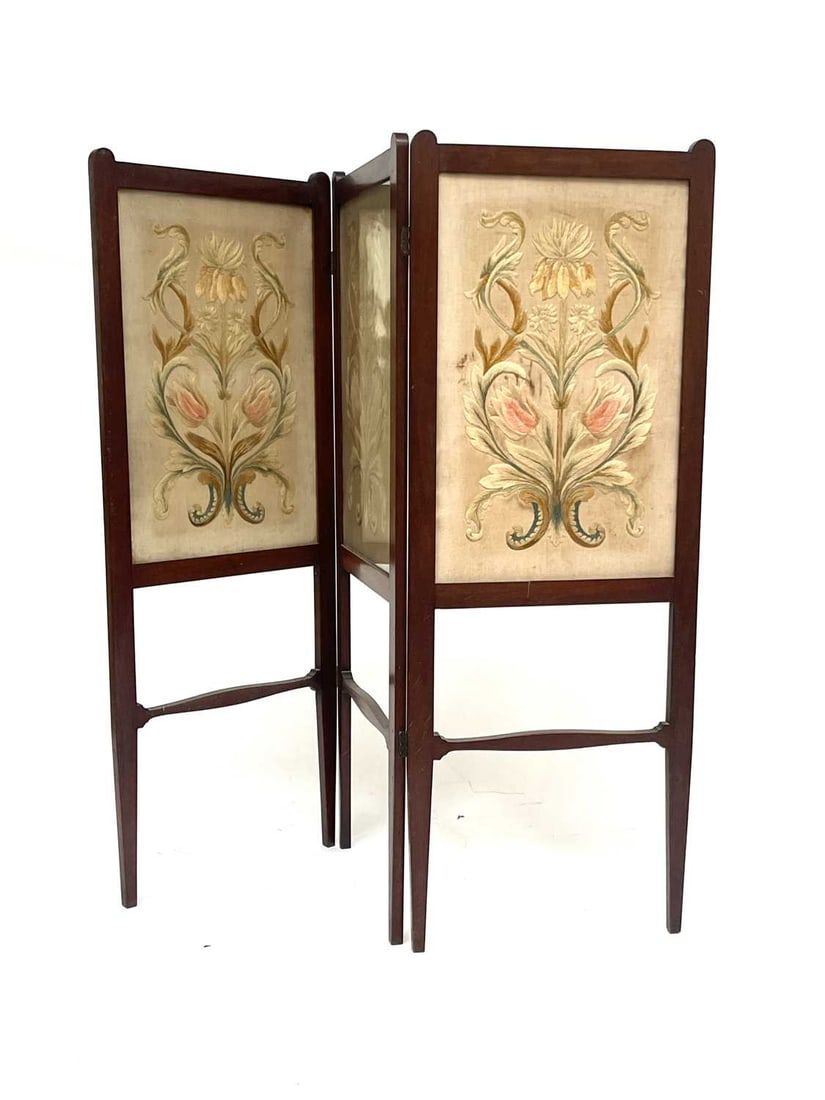 An Arts and Crafts walnut embroidered th: An Arts and Crafts walnut embroidered three fold screen, probably Morris and Co., in the style of George Walton, the foliate panels within frames on tapered legs united by shaped stretchers, 116cm hig