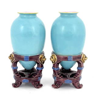 Christopher Dresser for Minton, a pair o: Christopher Dresser for Minton, a pair of Aesthetic Movement majolica vases, 1862, amphora form in integrated Oriental bracketed cage supports, relief moulded with lions masks and straps, turquoise an