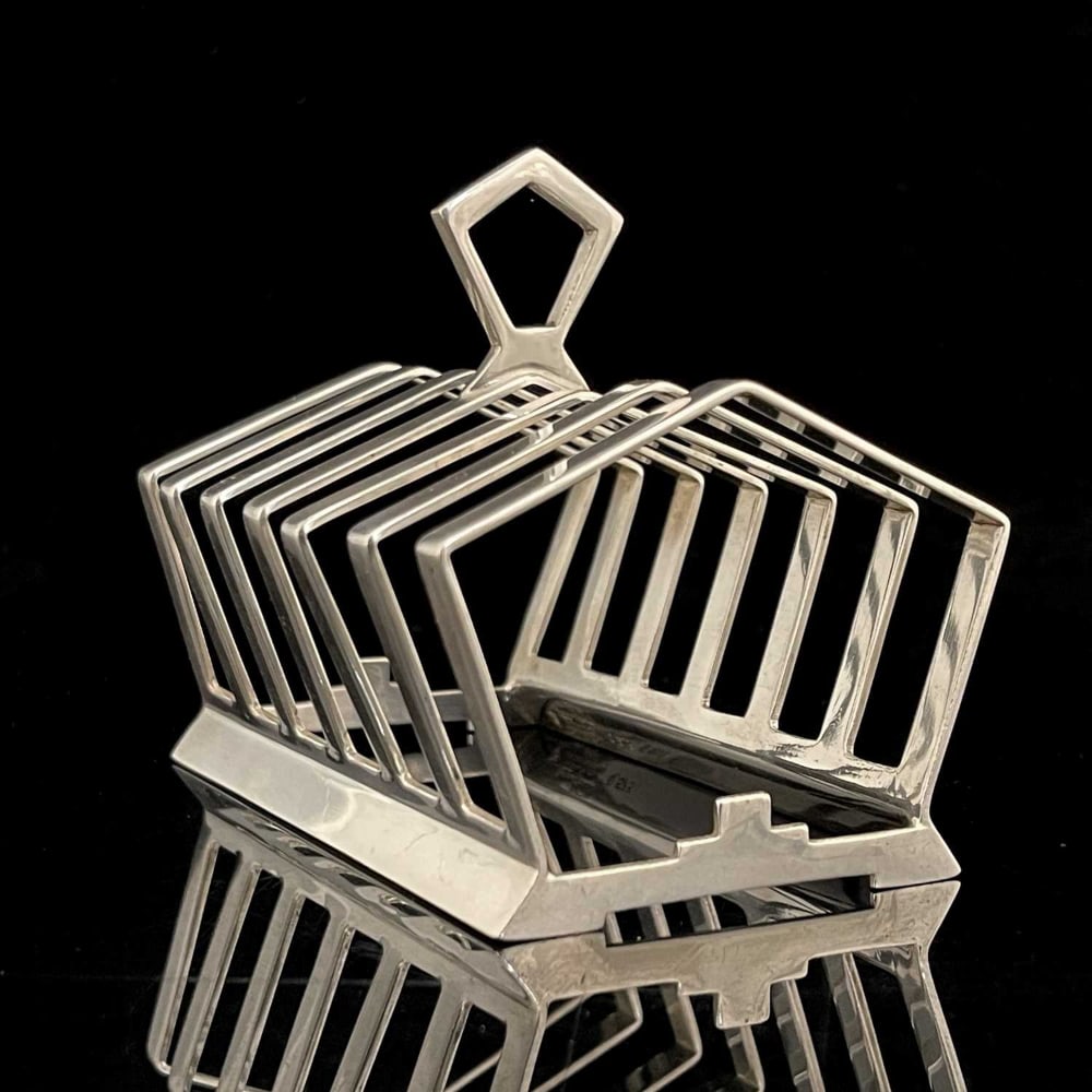 Keith Murray for Mappin and Webb, an Art: Keith Murray for Mappin and Webb, an Art Deco silver plated six division toast rack, circa 1934, the pentagonal dividers with central ring, united by stepped geometric bars, stamped marks W28157, 11.5