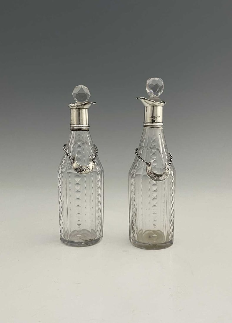 A pair of George III silver-mounted cut: A pair of George III silver-mounted cut glass sauce bottles, each with a faceted body and associated glass stopper, the silver collars with single spout, sponsor's mark rubbed, possibly George Gray, o