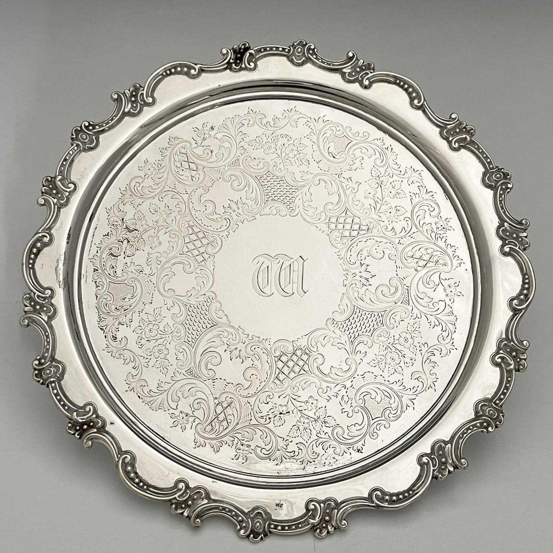 A Victorian silver salver, decorated wit: A Victorian silver salver, decorated with diaper work, flowerheads and foliate scrolls, initialled to the centre, the border with rococo scrolls, Atkin Brothers, Sheffield 1896, diameter 33cm, weight