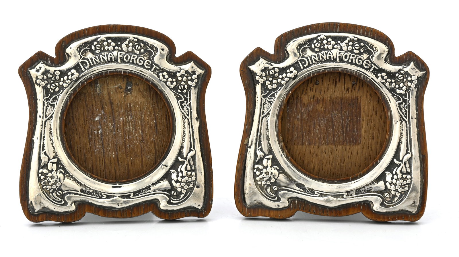 A pair of Arts and Crafts silver photo f: A pair of Arts and Crafts silver photo frames, Gourdel Vales and Co., Birmingham 1904, each of ogee bracket form embossed with foliate cartouche design with forget me nots and motto Dinna Forget, arou