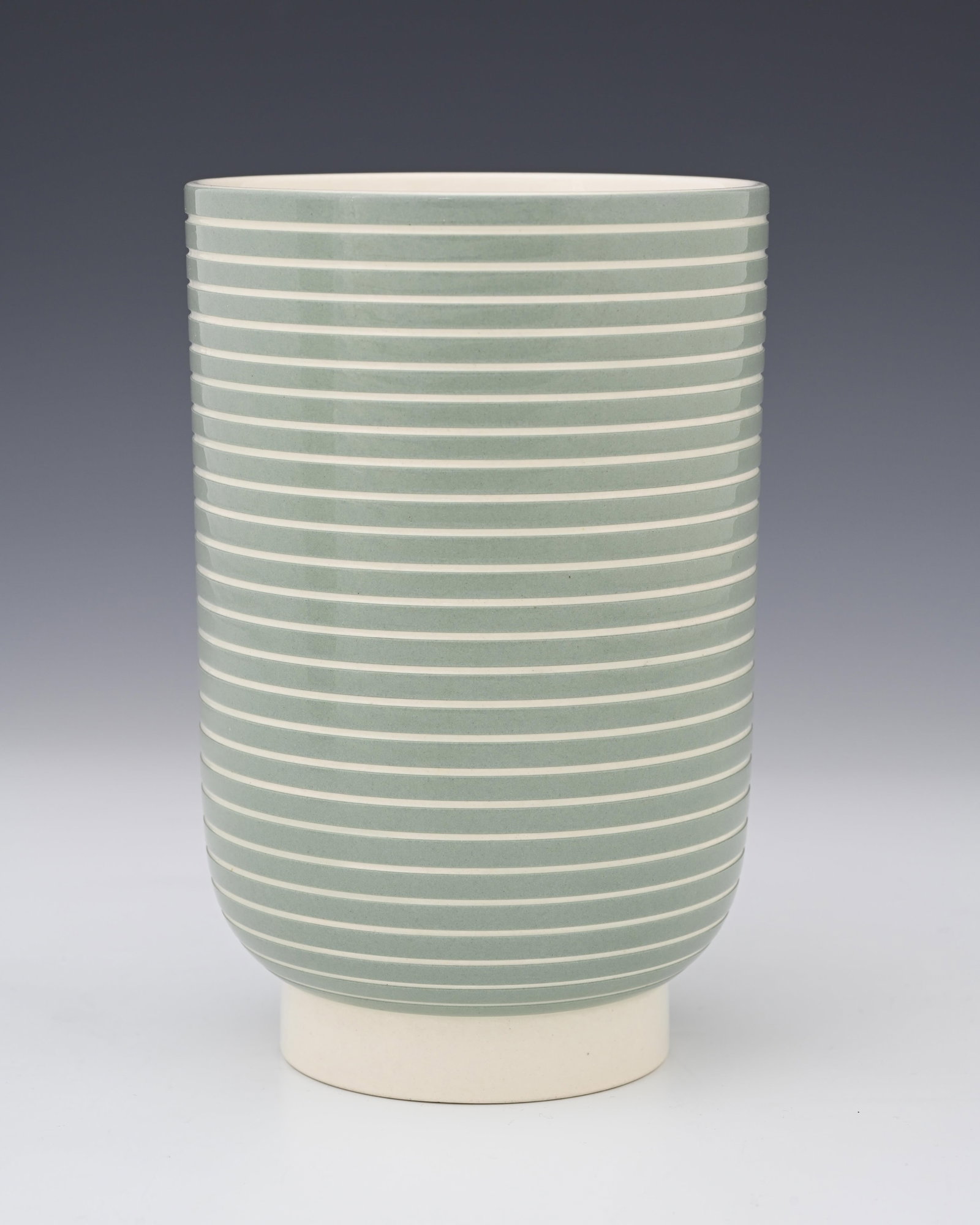 Keith Murray for Wedgwood, an Art Deo va: Keith Murray for Wedgwood, an Art Deo vase, footed cylindrical form, decorated with evenly spaced incised concentric bands, grey turquoise over cream, printed marks, 18.5cm high