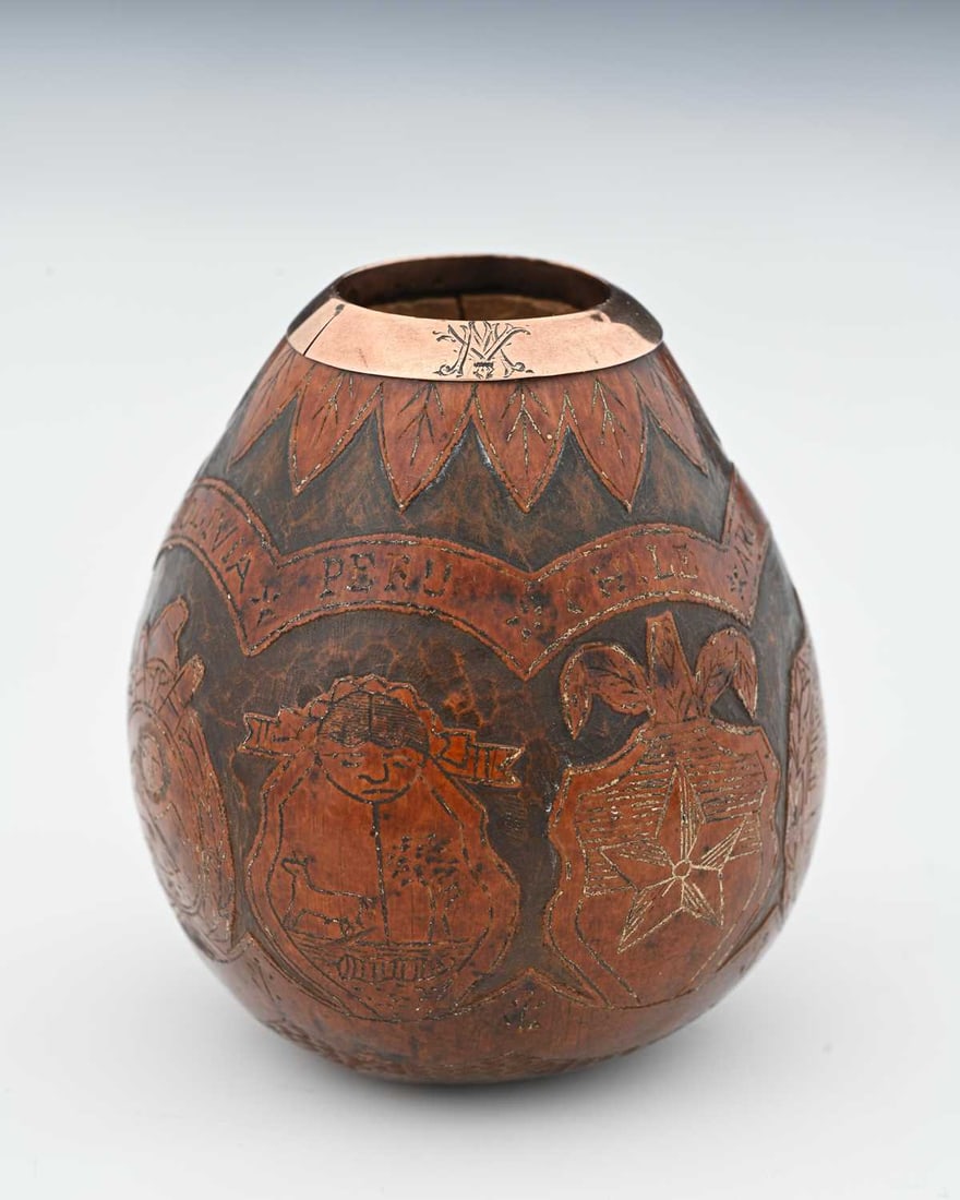 A South American rose-gold-coloured meta: A South American rose-gold-coloured metal carved gourd, possibly for mate, the exterior carved with vignettes of traditional motifs, the banner above with engraved names of countries including, 'PARAG