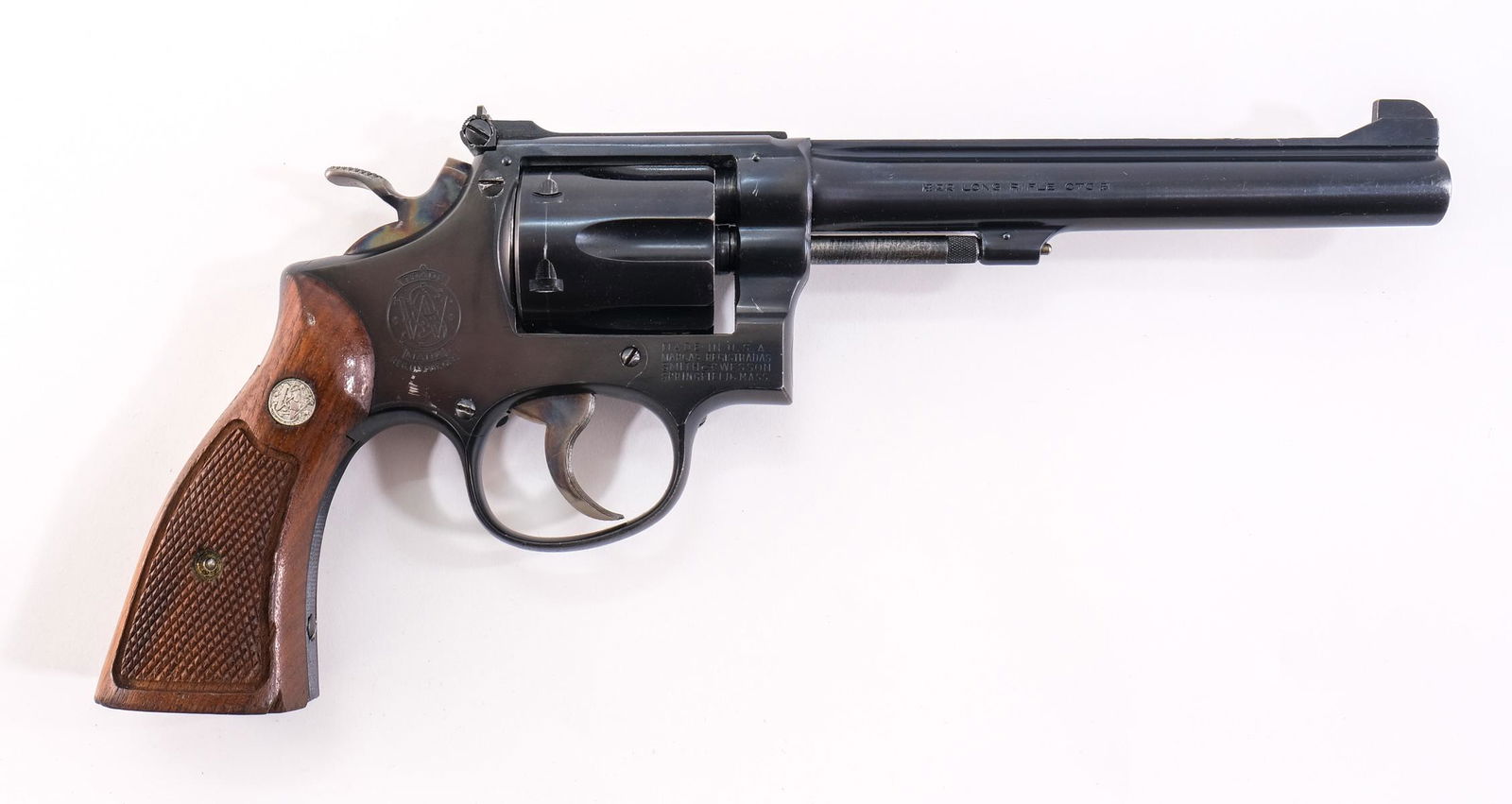 S&W K-22 Masterpiece .22lr Revolver: Description Smith & Wesson K 22 Masterpiece in 22 long rifle with a six round capacity and a 6" barrel. Checkered wood grip plates. Blued frame with serrated backstrap, cylinder and barrel. Case color