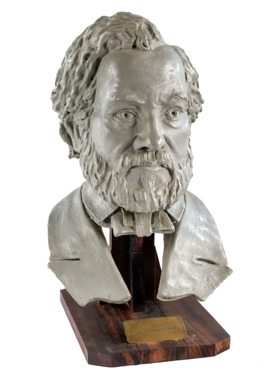 Colonel Samuel Colt Signed Mounted Plaster Bust: Description Colonel Samuel Colt painted plaster bust mounted on a wooden stand. Engraved brass name plate on the front of the wooden stand. The collar of the piece is signed by the artist: D. Joaquim.