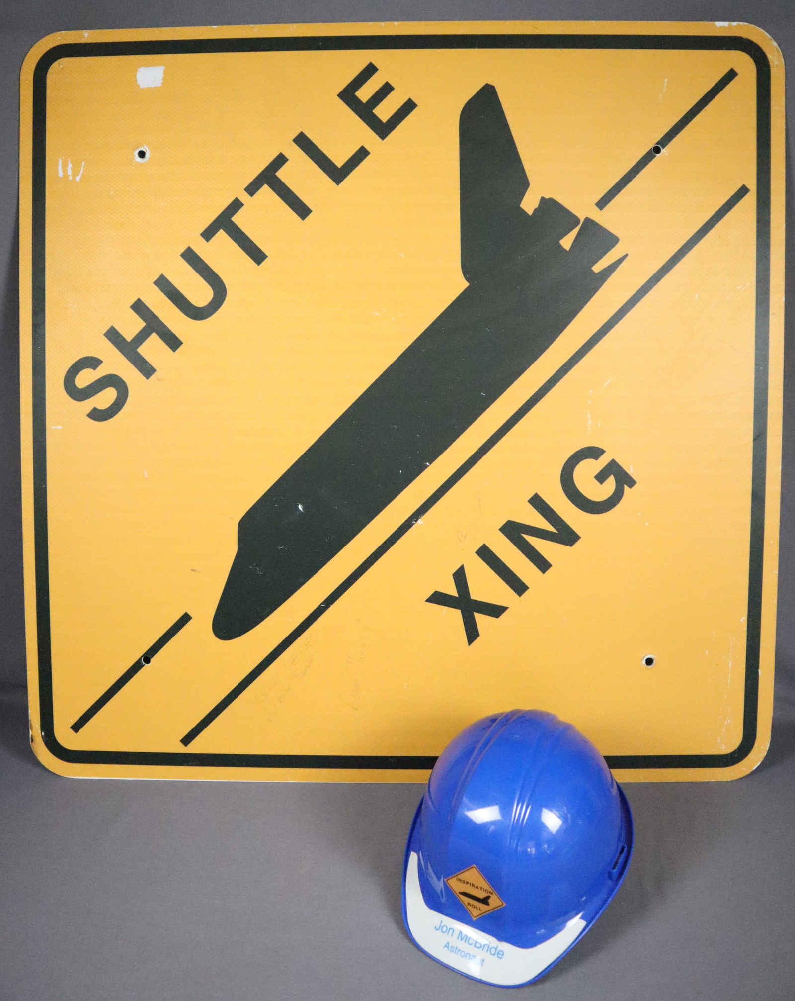 John McBride's Space Shuttle Crossing Sign & Hard Hat: From the personal collection of Astronaut Jon McBride an authentic "SHUTTLE XING" road sign that measures 36" x 36". There is also a Roll Out Hard Hat with "Shuttle Xing" sign on the hard hat front th