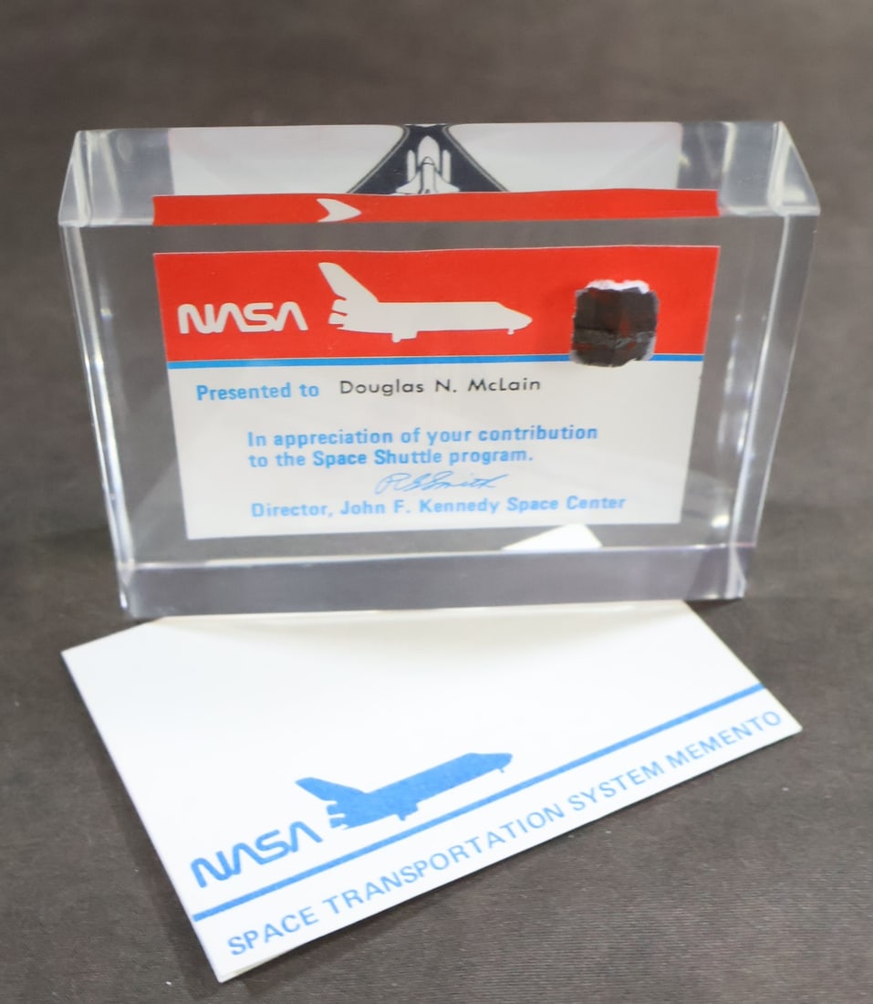 Flown "Columbia" Thermal Protection Tile Section Lucite: This Flown Thermal Protection Tile Heat Shield Lucite presentation is dedicated to Douglas N. McLain and features a 1/2" x 1/2" piece of heat shield material. The tile section is cut from a damaged