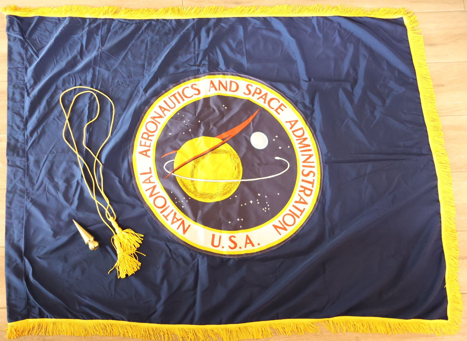 NASA Headquarters Meatball Flag with Pole Topper & Rope: This flag is reportedly from the NASA Headquarters building. It has a high quality NASA Meatball emblem that has been sewn onto the flag along with gold tassels around the edges. This flag measures 68