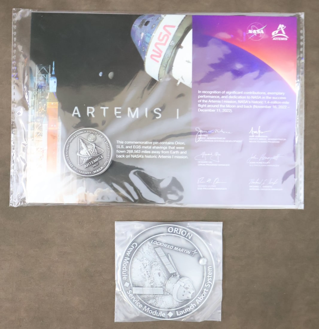 Artemis 1 Flown Metal Pin & Mission Coin: An Artemis 1 mission coin/pin commemorating NASA'S Artemis 1 mission. This item contains metal shavings from Orion, SLS and EGS that were flown 268,563 miles away from Earth and back. This pin is in