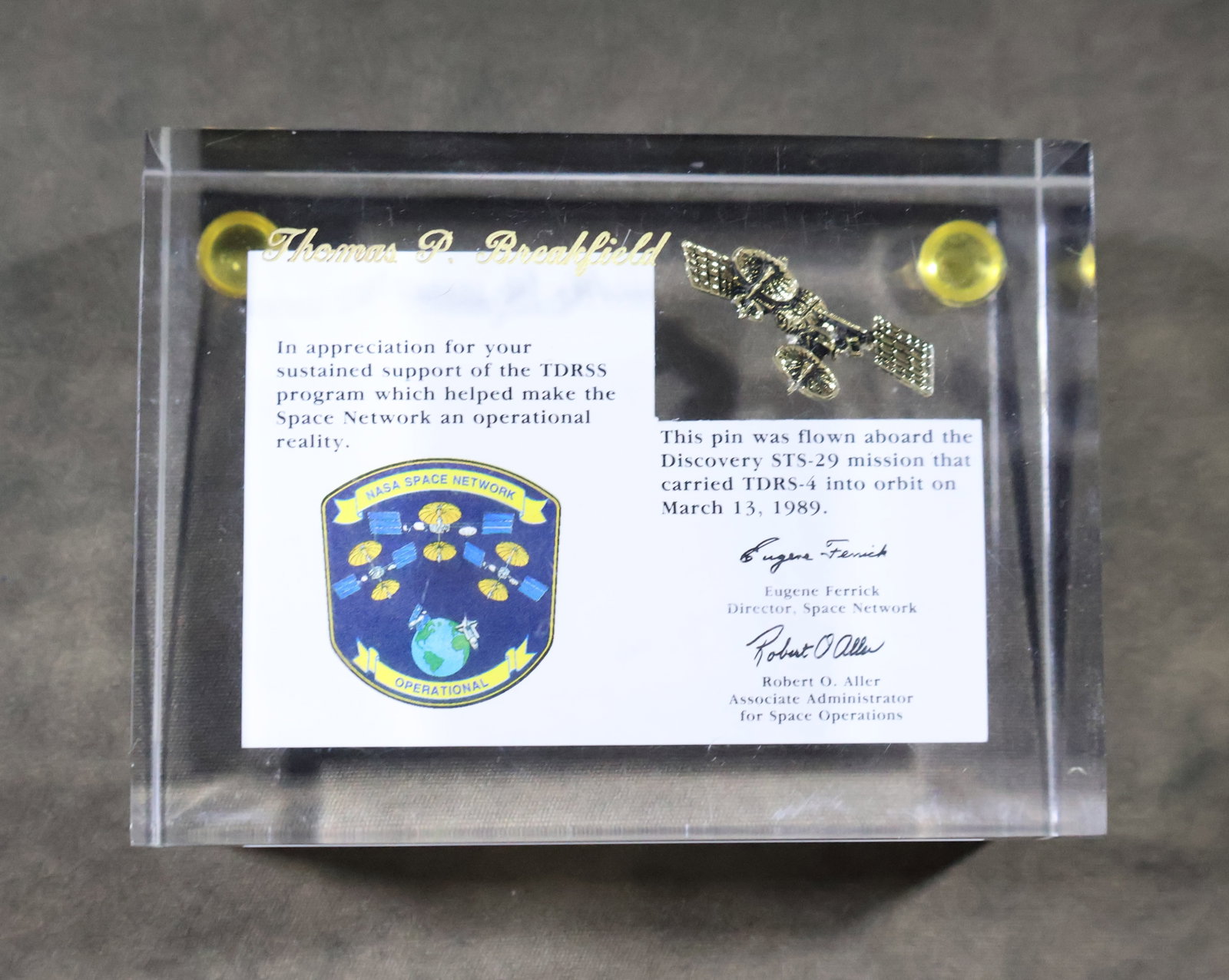 STS-29 Flown TDRSS Pin Lucite: This Flown TDRS (Tracking & Data Relay Satellite) pin Lucite was presented to Paul Thomas Breakfield, III who was a Deputy Director of Shuttle Engineering and Director of Payload Flight Operations
