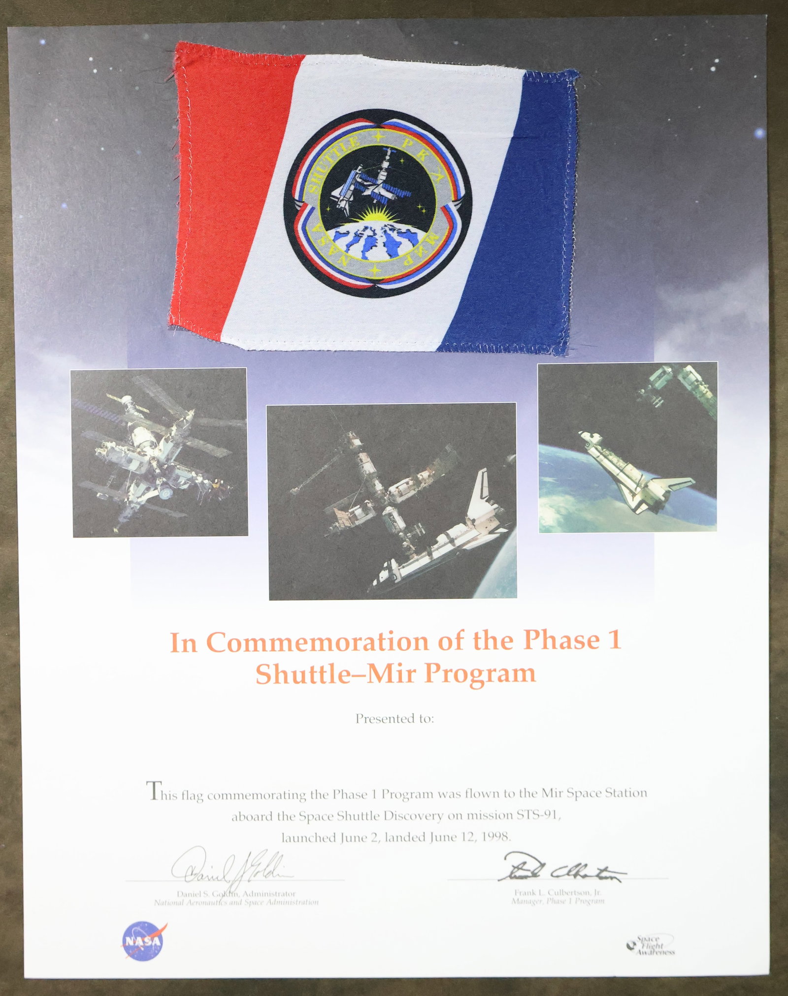 STS-91 'Unawarded' Flown Shuttle-Mir Program Flag Award: A NASA Space Flight Awareness presentation award. This 11" x 14" presentation award displays a 4 1/4" x 6" Shuttle-Mir flag. This Shuttle-Mir flag commemorates the Phase 1 Program and was Flown to the
