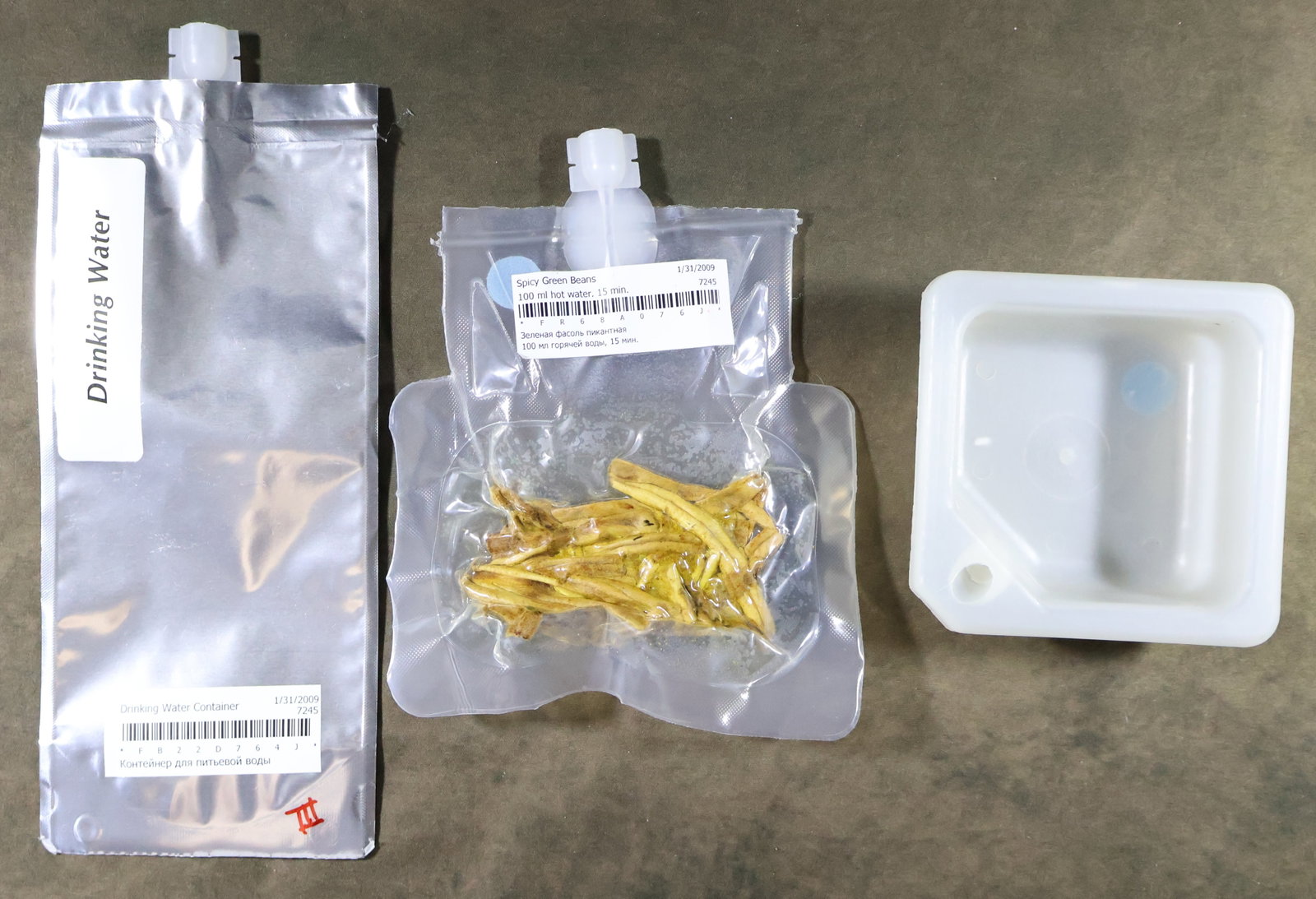 3 - Space Shuttle "Space Food" Items: Three Space Food related items from the Space Shuttle era. Included is a Drinking Water Container displaying the USB barcode and the blue Velcro attachment dot. This item was unused and never filled.
