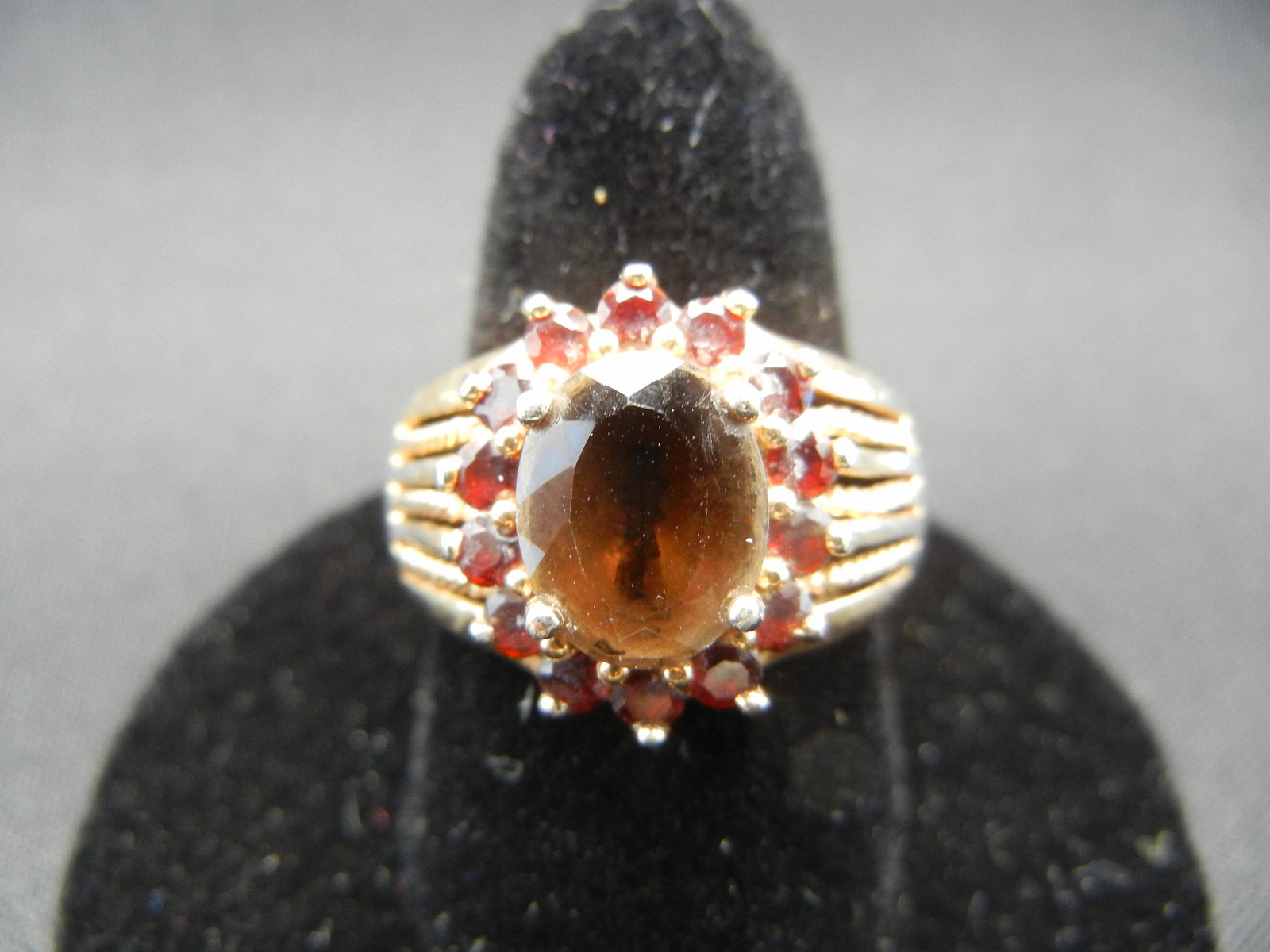 Ladies sterling ring with 1 carat Garnet colored stone: Ladies sterling ring with 1 carat Garnet colored stone circled with small garnet colored stone. Size 8. ($12.00)