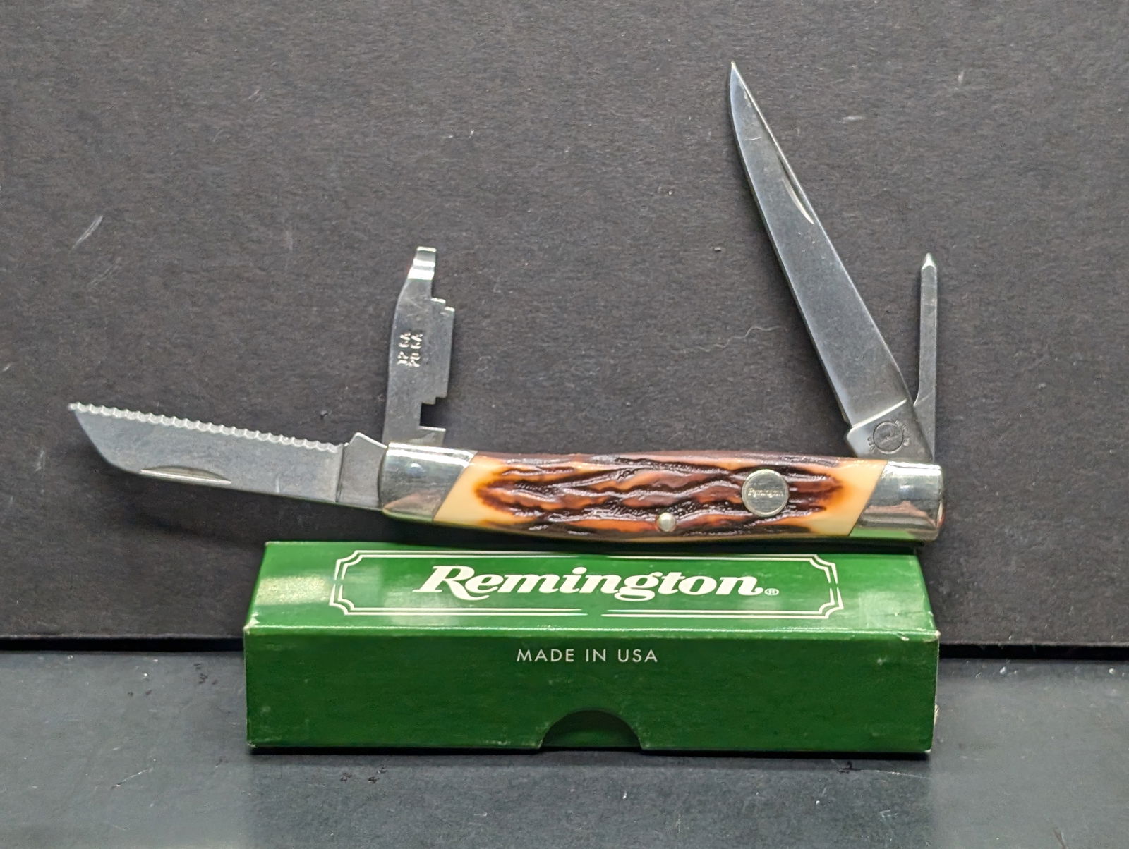Remington #18565 Folding Waterfowl Knife Delrin stag handles Mint, old stock in box with paperwork: U.S. made Remington model R2 multi blade knife with jigged amber/brown “bone stag” Delrin scales, brass liners, nickel silver bolsters and Remington medallion shield. Implements: long clip poi