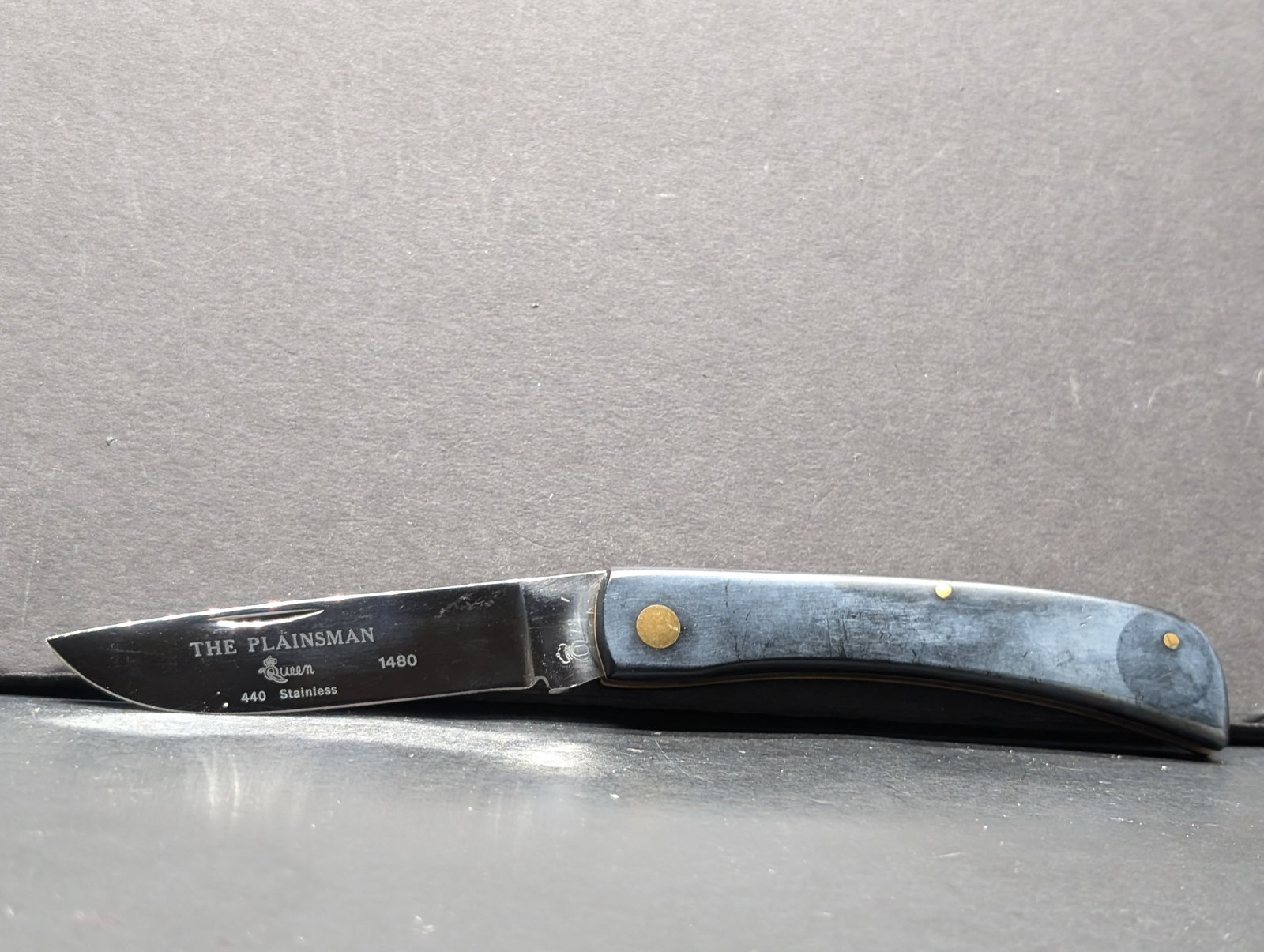 Queen Cutlery "The Plainsman" #1480 Vintage 1978 Pocket Knife 440 SS, Blade is embossed with "The: Queen Plainsman 1480 Folding Knife. Features a classic design with a 440 stainless steel blade, marked with "The Plainsman 1480." Blade length is approximately 3.5 inches, based on the ruler in the im