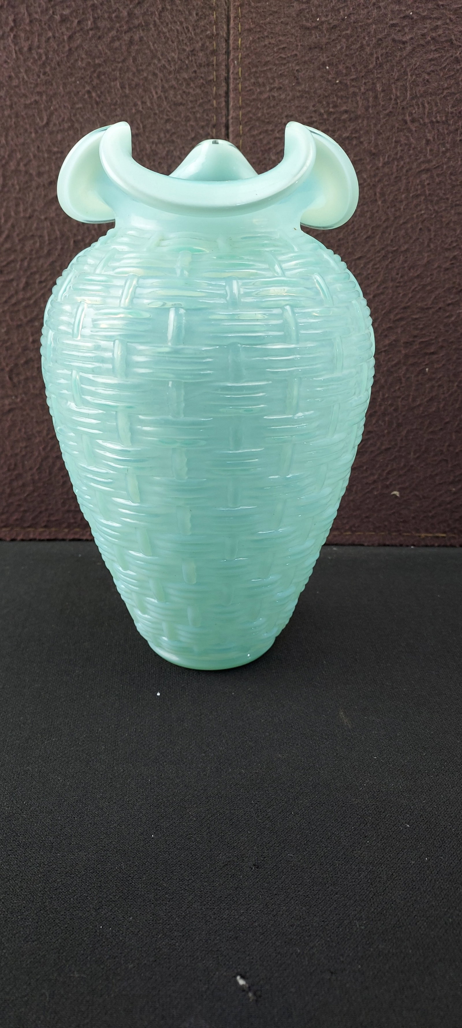 Circa 1960s Fenton Blue Green Opalescent Basketweave Ruffled Vase: A vintage Fenton Art Glass Basketweave Ruffled Vase. Crafted from light greenish-blue opalescent glass, this decorative vessel features a prominent, raised basketweave pattern covering its entire bell
