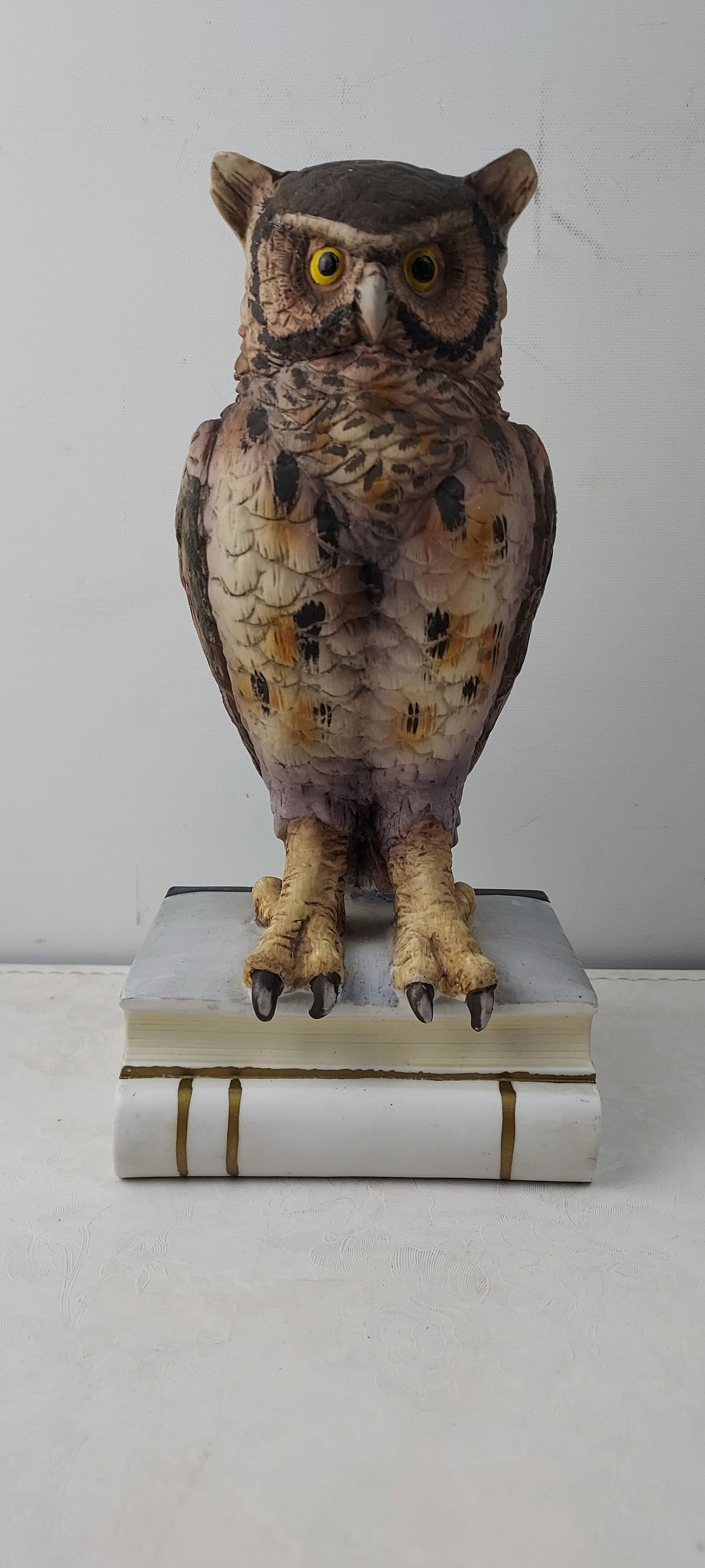 Andrea by Sadek Great Horned Owl on Books Porcelain Figurine: This is an Andrea by Sadek Great Horned Owl Porcelain Figurine. The hand-painted figurine depicts a realistic owl with prominent ear tufts, rendered in varying shades of brown, tan, cream, and black t