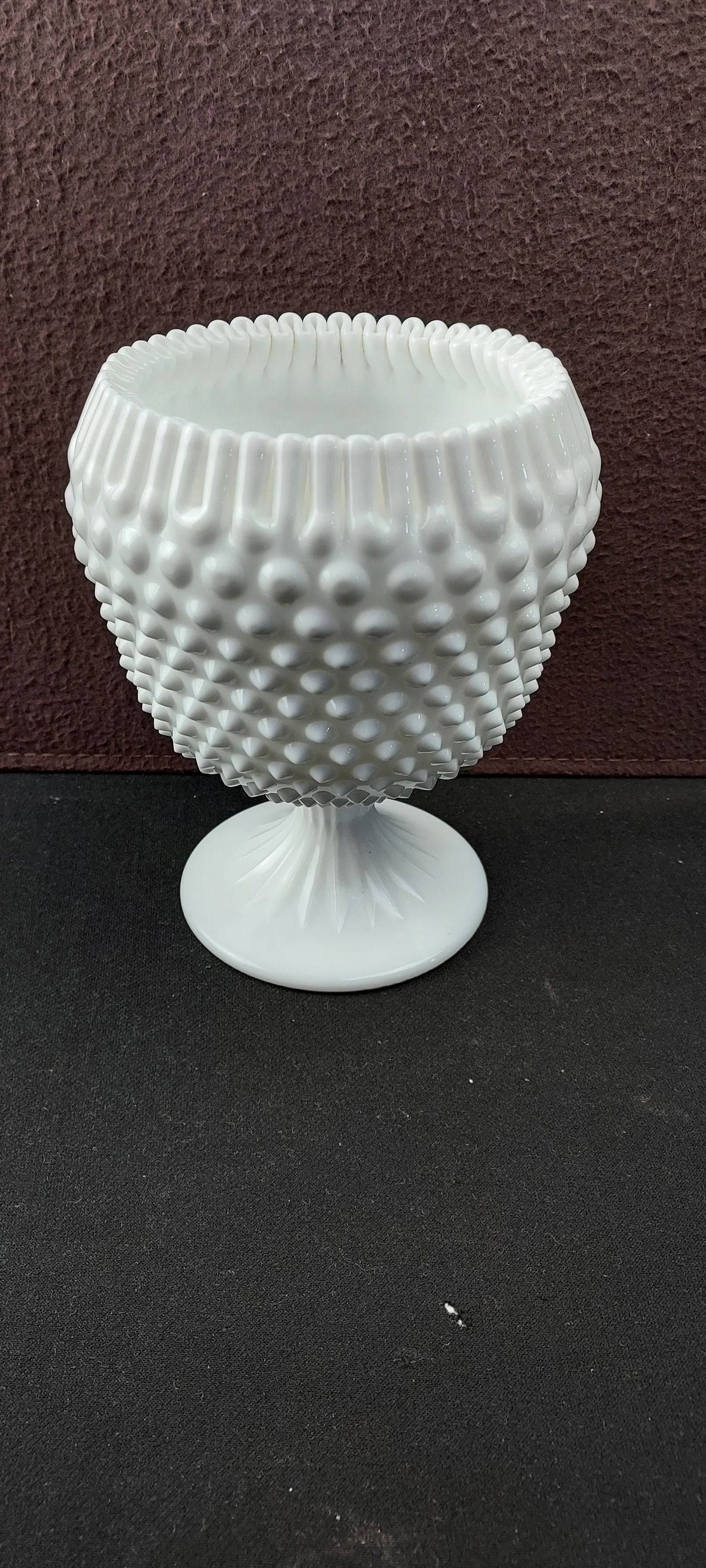 Vintage Fenton Milk Glass Hobnail Pedestal Ivy Ball Vase Ribbon Edge: This listing presents a vintage Fenton Milk Glass Hobnail Pedestal Ivy Ball Vase. Crafted from opaque white milk glass, the piece features the iconic hobnail pattern covering its bulbous body. It rest