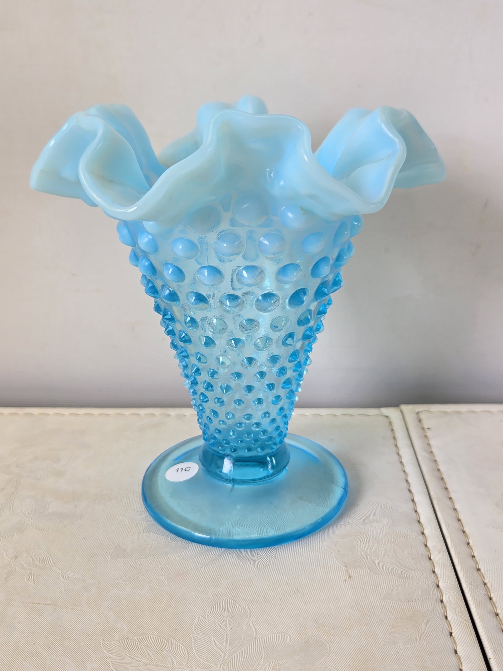Vintage Fenton Glass Blue Opalescent Hobnail Ruffled Vase, approx. 5 3/4" Tall: A vintage Fenton Glass vase, featuring the iconic Hobnail pattern in Blue Opalescent glass. The vase presents a flared, ruffled opalescent rim that transitions into a hobnail-patterned body, tapering 